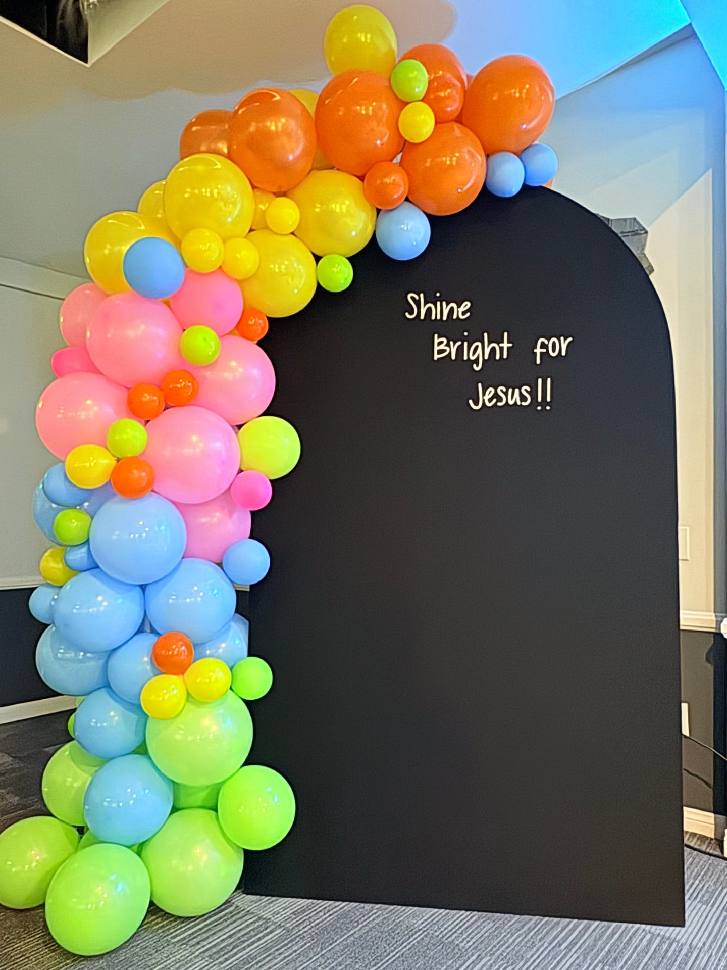 Colorful organic balloon garland on a black arched backdrop